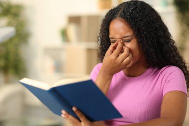 Siyah kitap okuyucusu evde otururken göz yorgunluğu çekiyor.