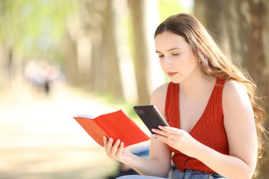 Kadın parkta telefon ve kağıt kullanmayı planlıyor.