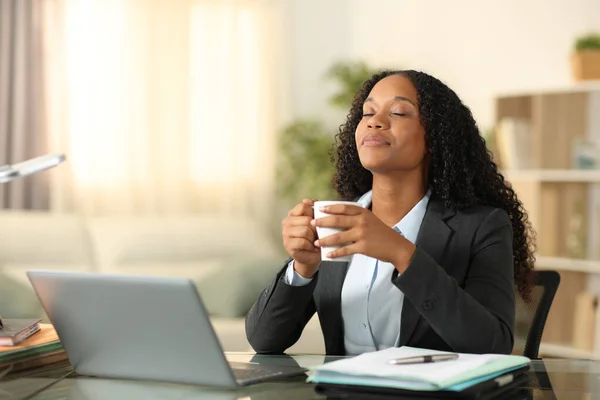 Black teleworker relieving stress breathing drinking coffee at home