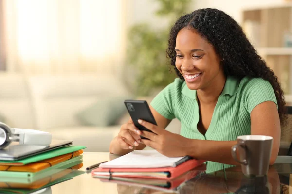 stock image Happy black student checking phone studying at home