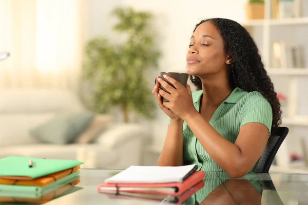 Black student relaxing drinking coffee sitting and breathing at home