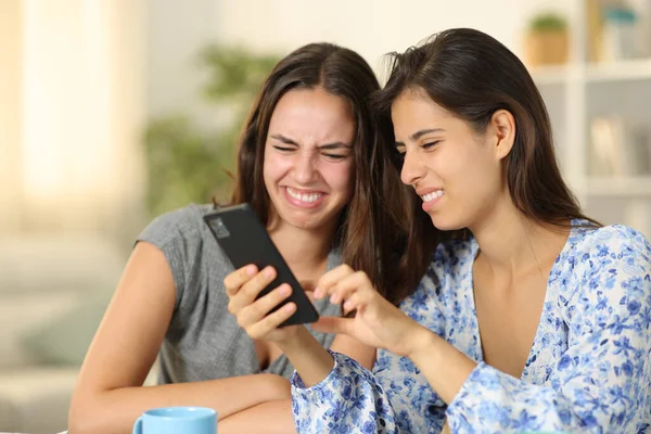 Stock image Disgusted women checking nasty cell phone content at home