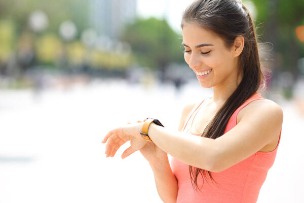 Happy runner checking time in smartwatch in the street