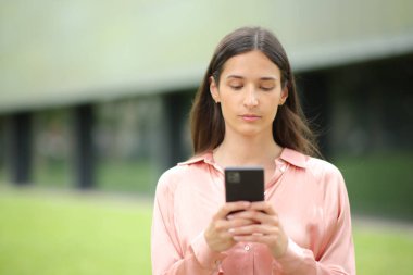 Sana doğru yürürken cep telefonu kullanan ciddi bir kadının portresi.