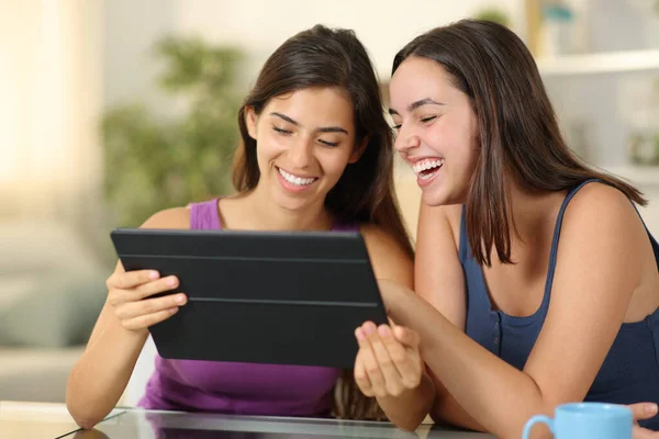 快乐的女人在家里用平板电脑笑 免版税图库图片