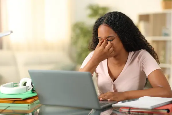 Black student suffering eyestrain e-learning with a laptop at home