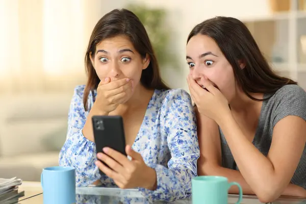 Amazed women watching media on phone at home