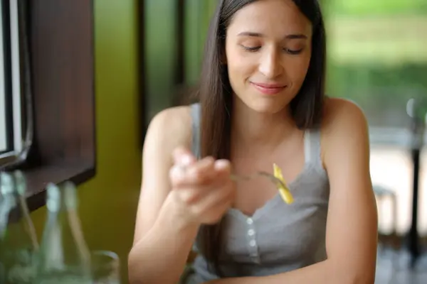 Front view portrait of a woman in a restaurant eating potato fries