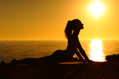 Gün batımında yoga yapan bir yoganın yan görüş portresi.