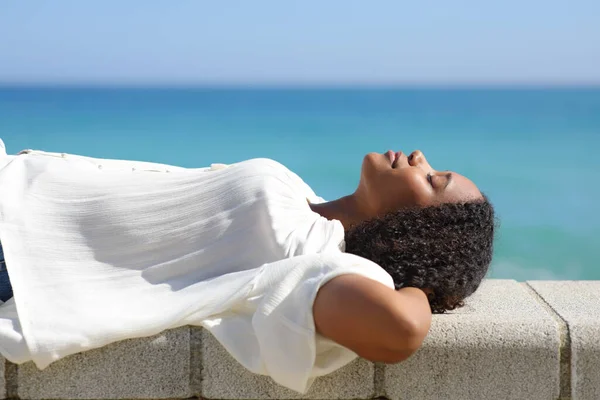 夏日晴天 一位黑人妇女躺在海滩上 图库图片