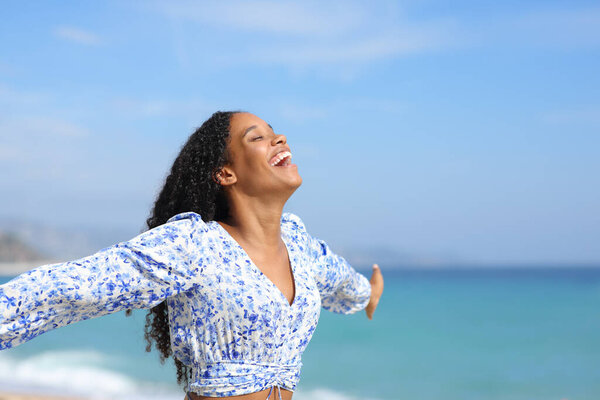 Joyful black woman celebrating good day on the beach