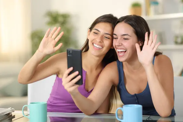 stock image Two happy roommates having videocall on phone at home