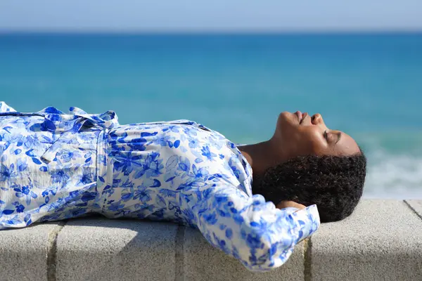 Profile of a relaxed black woman lying on the beach resting