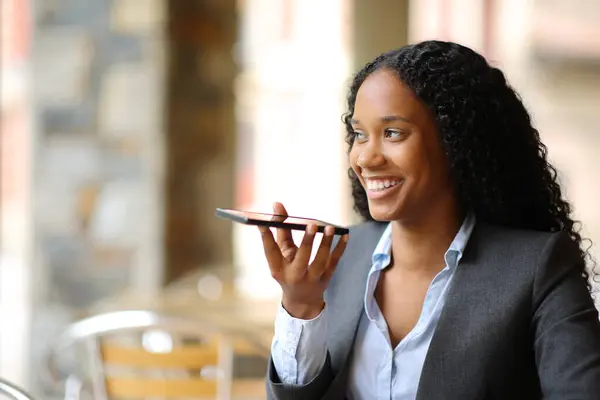 Happy black executive dictating message on phone in a coffee shop
