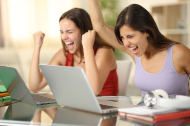 Heyecanlı öğrenciler evde dizüstü bilgisayarları kontrol ederek başarıyı kutluyor