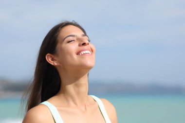 Kumsalda nefes alan ve yazın gülümseyen mutlu kadın.