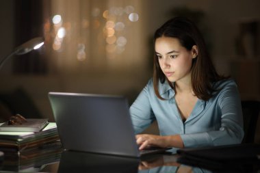 Gece evde dizüstü bilgisayarla çalışan serbest çalışan bir kadın.