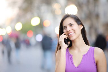 Sokakta telefonla konuşan mutlu bir kadın.