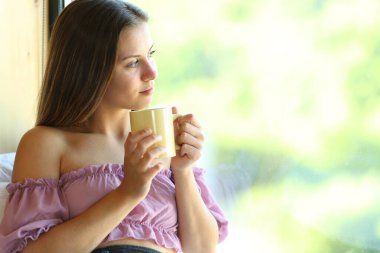 Pencereden bakan ve evde çay içen bir çocuk.