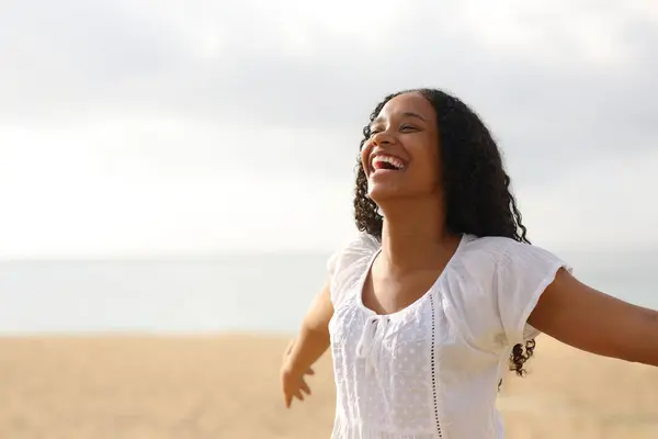 快乐的黑人女人张开双臂 在海滩上大笑 图库照片