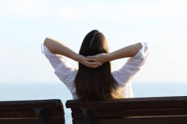 Sahilde bir bankta rahatlayan bir kadının arka plan portresi.