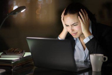 Worried tele worker in the night checking laptop complaining clipart