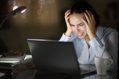 Desperate businesswoman checking laptop in the night at homeoffice clipart