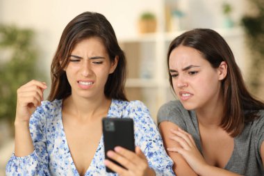 Two friends watching nasty content on phone at home clipart
