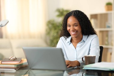 Evde dizüstü bilgisayarla çalışan mutlu siyahi serbest çalışan.