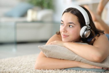 Kulaklıklı düşünceli kadın podcast 'i dinliyor halının kenarına bakıyor.