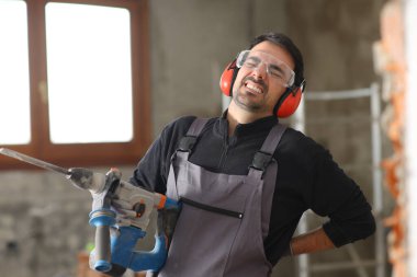 İnşaat işçisi sırt ağrısı çekiyor. Tadilat altındaki bir evde çalışıyor.