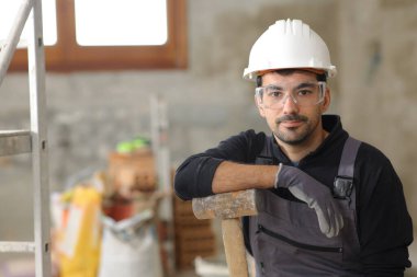 Tadilat altındaki bir evde poz veren ciddi bir inşaat işçisinin portresi.