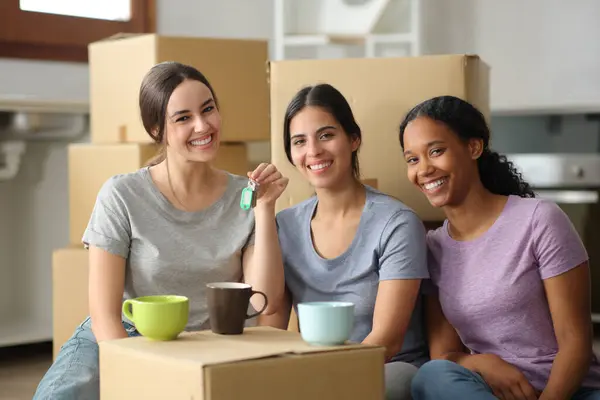 Stock image Three happy roommates showing keys moving home looking at camera