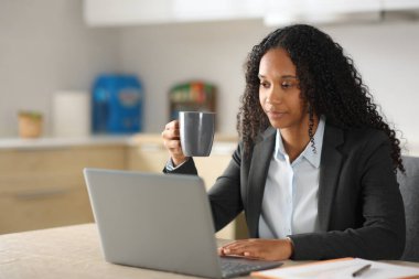 Evdeki mutfakta çalışan siyah yöneticiler dizüstü bilgisayar kullanıyor.