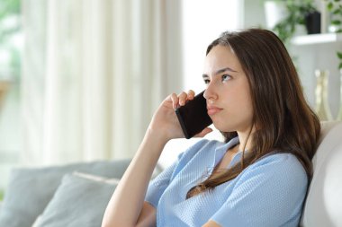 Telefon görüşmesine katılan bunalmış bir kadın evde oturuyor.