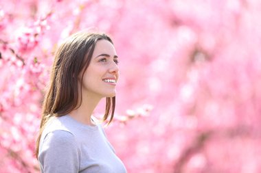 Çiçekli şeftali ağacının manzarasını seyreden mutlu bir kadın.