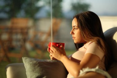 Gün batımında kahve içen ciddi bir kadının profili.