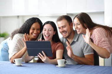 Mutlu ırklar arası arkadaşlar, evdeki mutfaktaki tablette video çağrısı var.