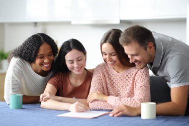 Dört mutlu ev arkadaşı evdeki mutfakta kontrat imzalıyor.