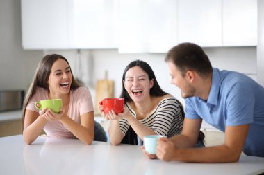 Mutfakta konuşan ve evde kahve içen ırklar arası mutlu ev arkadaşları.