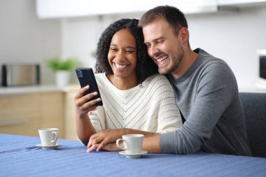 Mutfaktaki mutlu çift evdeki akıllı telefonu kontrol ediyor.