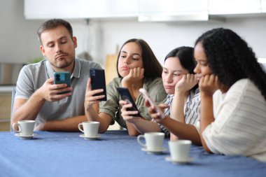 Evdeki mutfakta akıllı telefonlarını kullanarak onları görmezden gelen sıkıcı arkadaşlar.