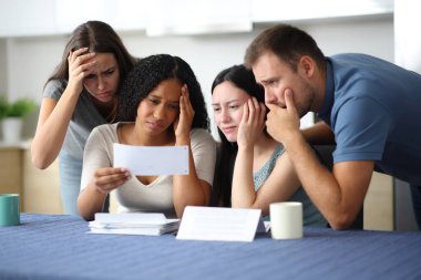 Dört endişeli ırklar arası arkadaş evdeki mutfakta faturaları kontrol ediyor.