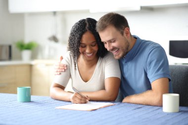 Mutlu ve sevecen bir çift evdeki mutfakta kağıt imzalıyor.