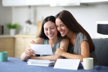 Mutlu ırklar arası lezbiyen çift mutfaktaki faturayı kontrol ediyor.