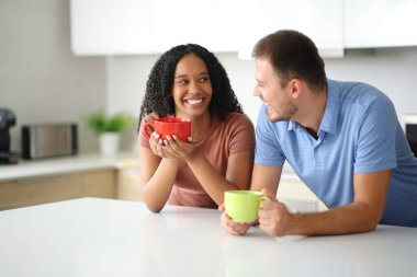 Mutlu ırklar arası çiftler evdeki mutfakta konuşuyor ve içiyor.