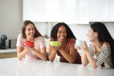 Evde mutfakta konuşan ve gülen üç kadın.