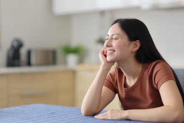 Mutlu Asyalı kadın evde mutfakta dinleniyor ve dinleniyor.