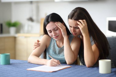 Evdeki mutfakta gazete okuyan, ırklar arası lezbiyen bir çift için endişeleniyor.