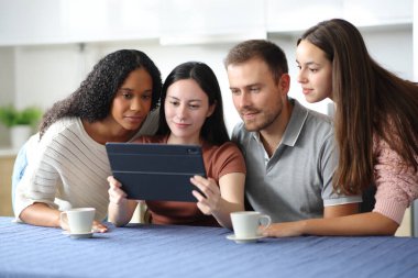 Dört ırklar arası arkadaş evdeki mutfakta tablet içeriğini kontrol ediyor.